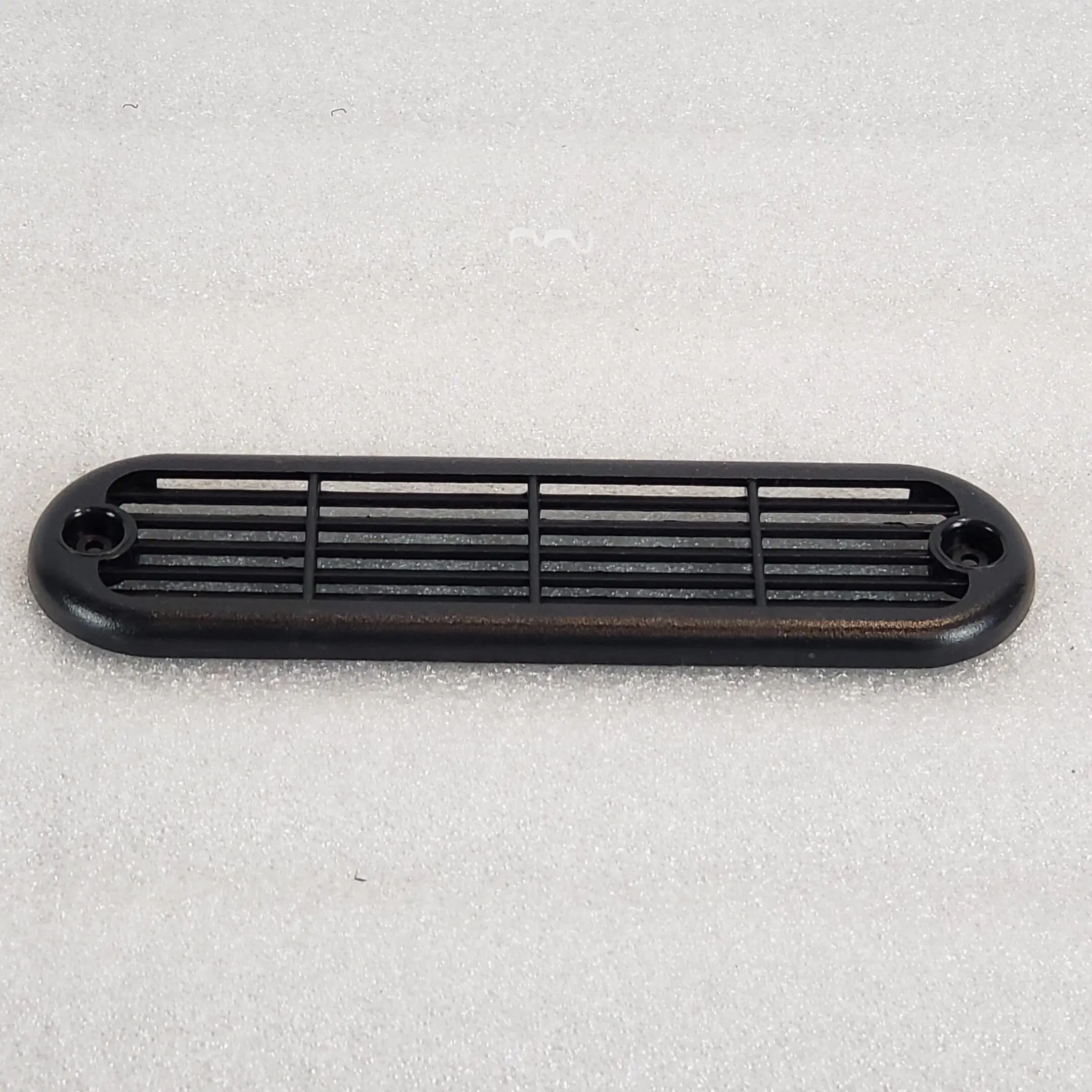 A black plastic air vent on top of a white surface.