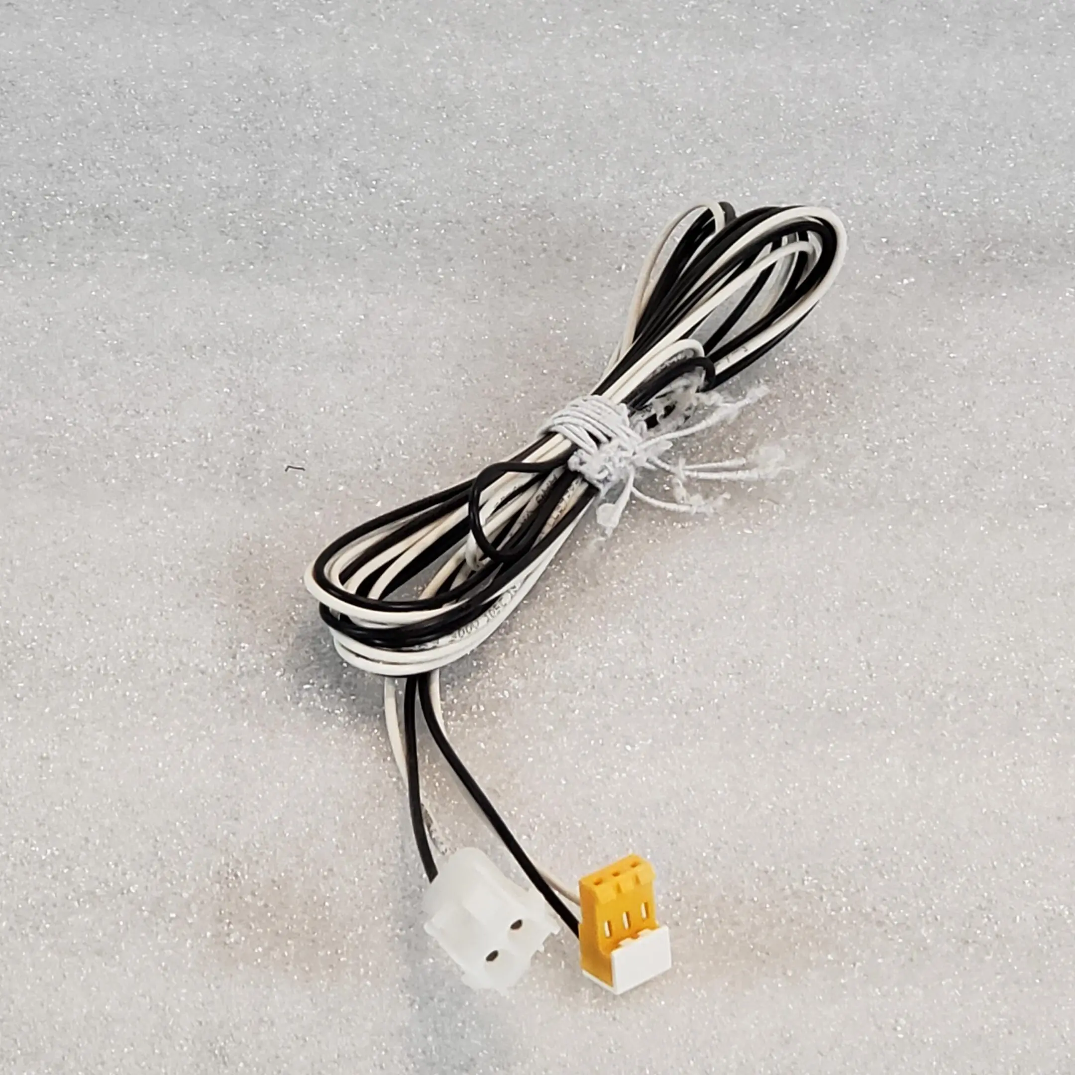 A white and black wire is laying on the floor