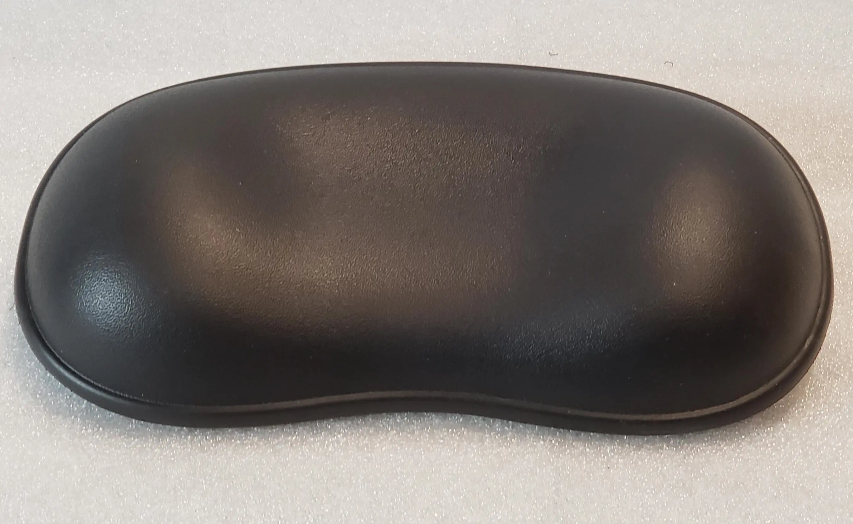 A black pillow sitting on top of a white floor.