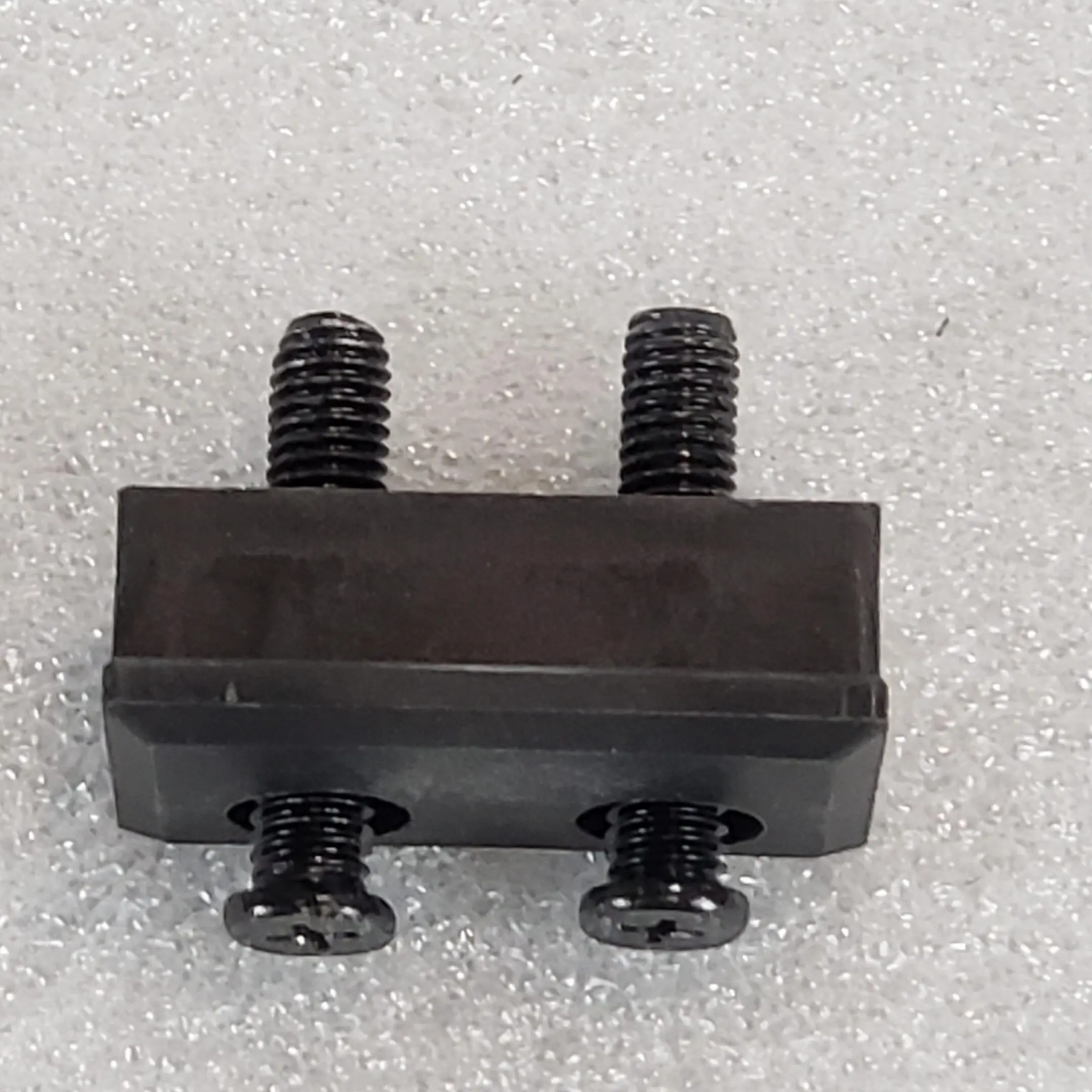 A black piece of metal with two bolts on it.