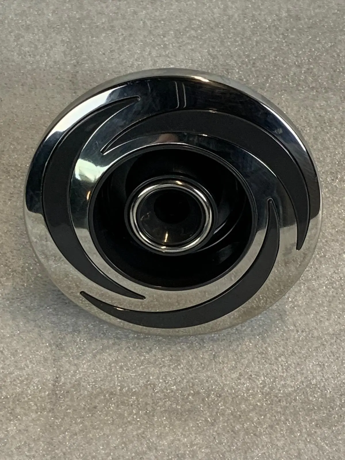 A chrome and black knob on the floor.