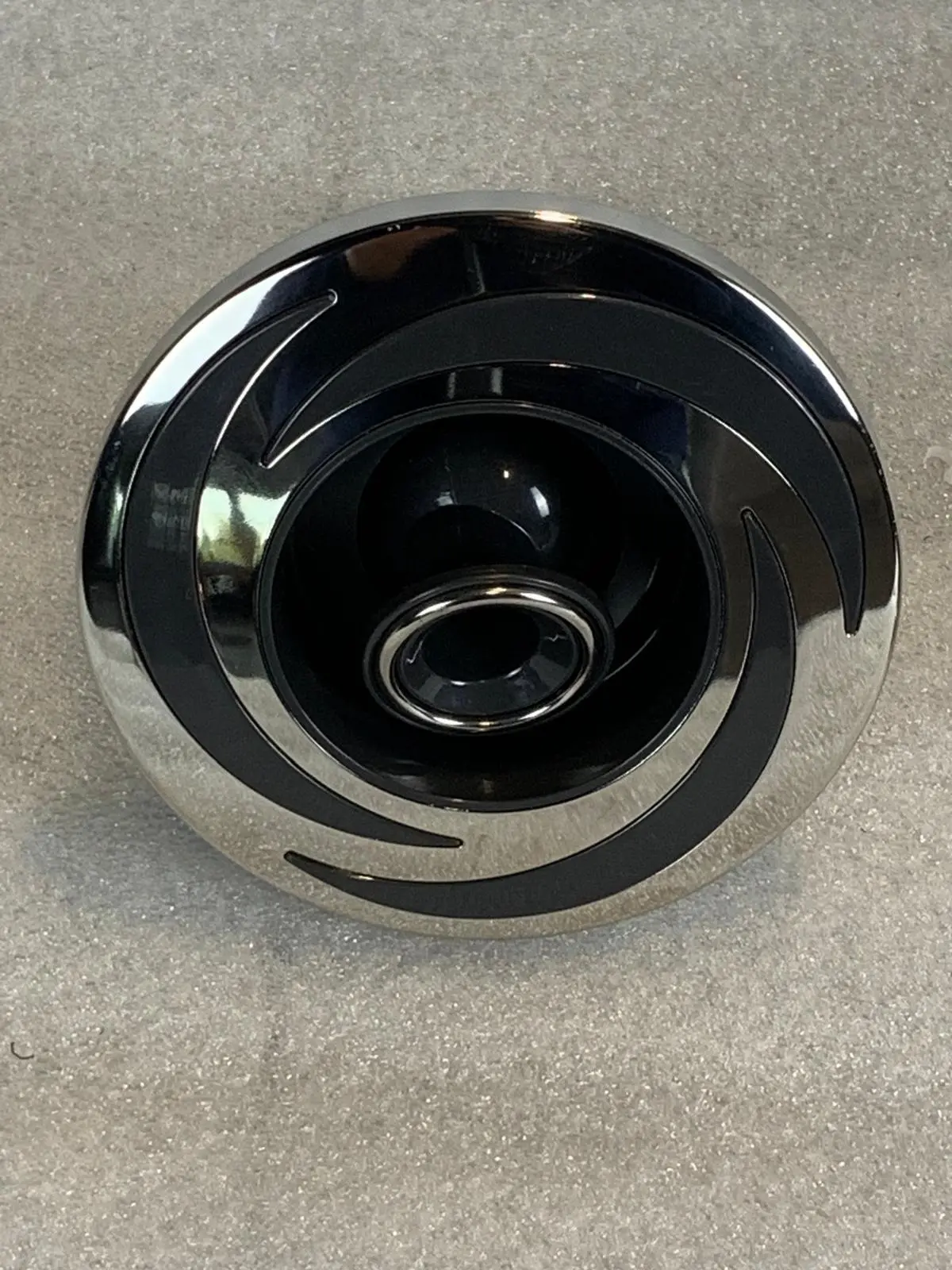 A chrome and black knob on the floor