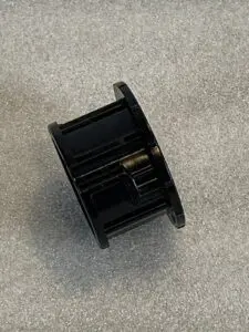 A black plastic object sitting on top of the floor.