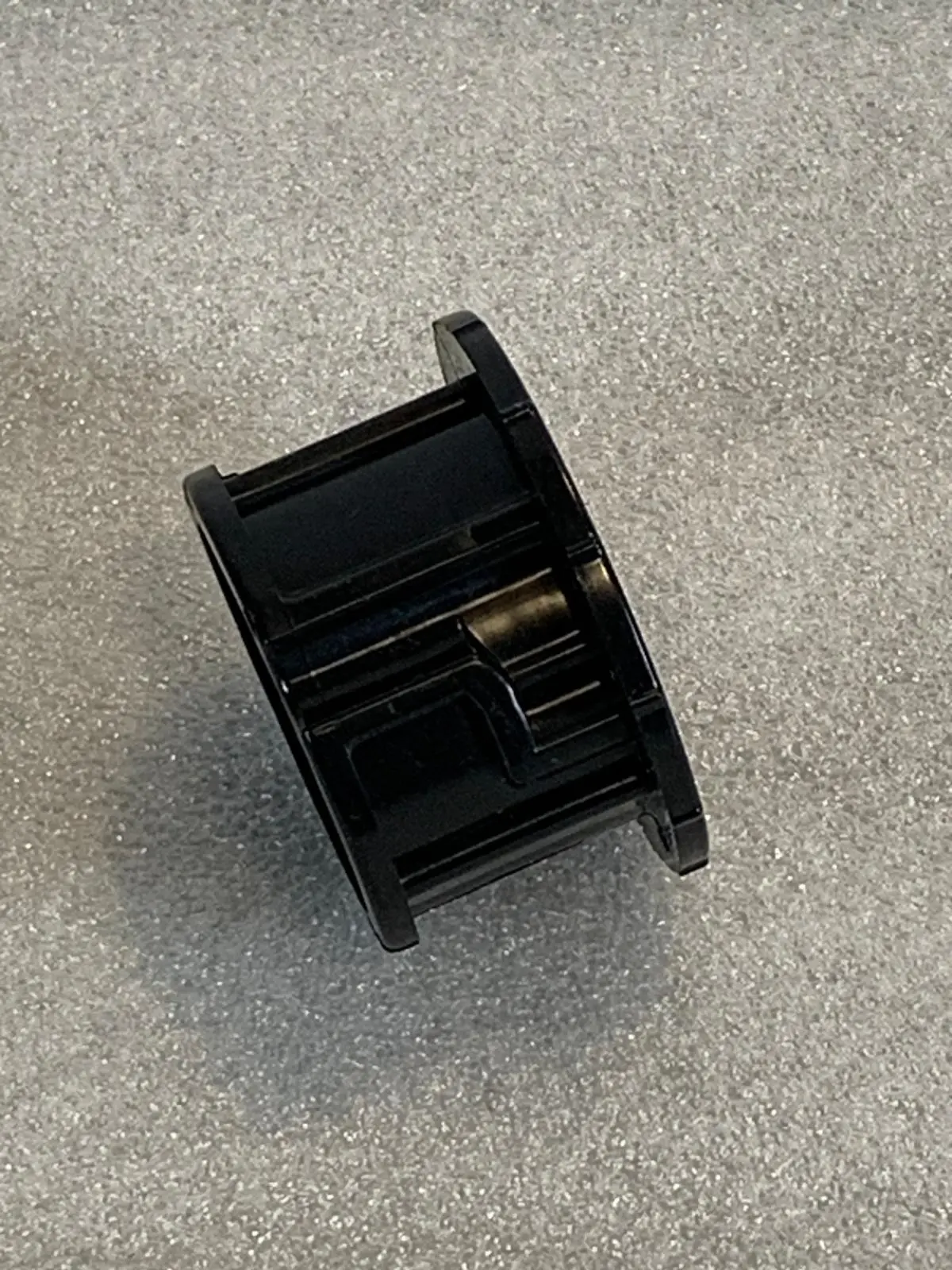 A black plastic object sitting on top of the floor.
