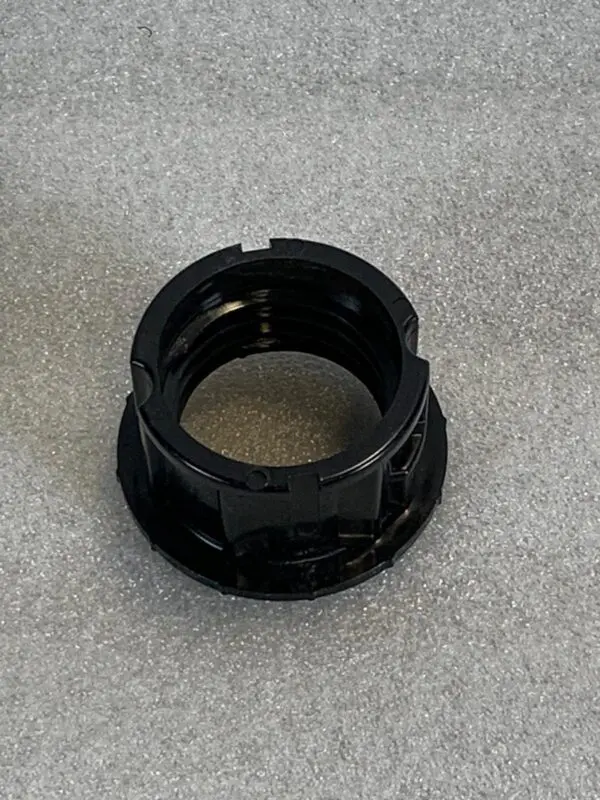 A black plastic nut sitting on top of the floor.