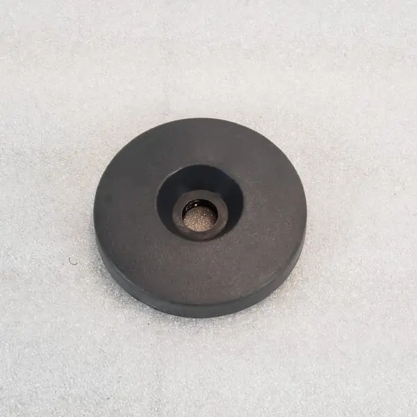 A black round object sitting on top of a white surface.