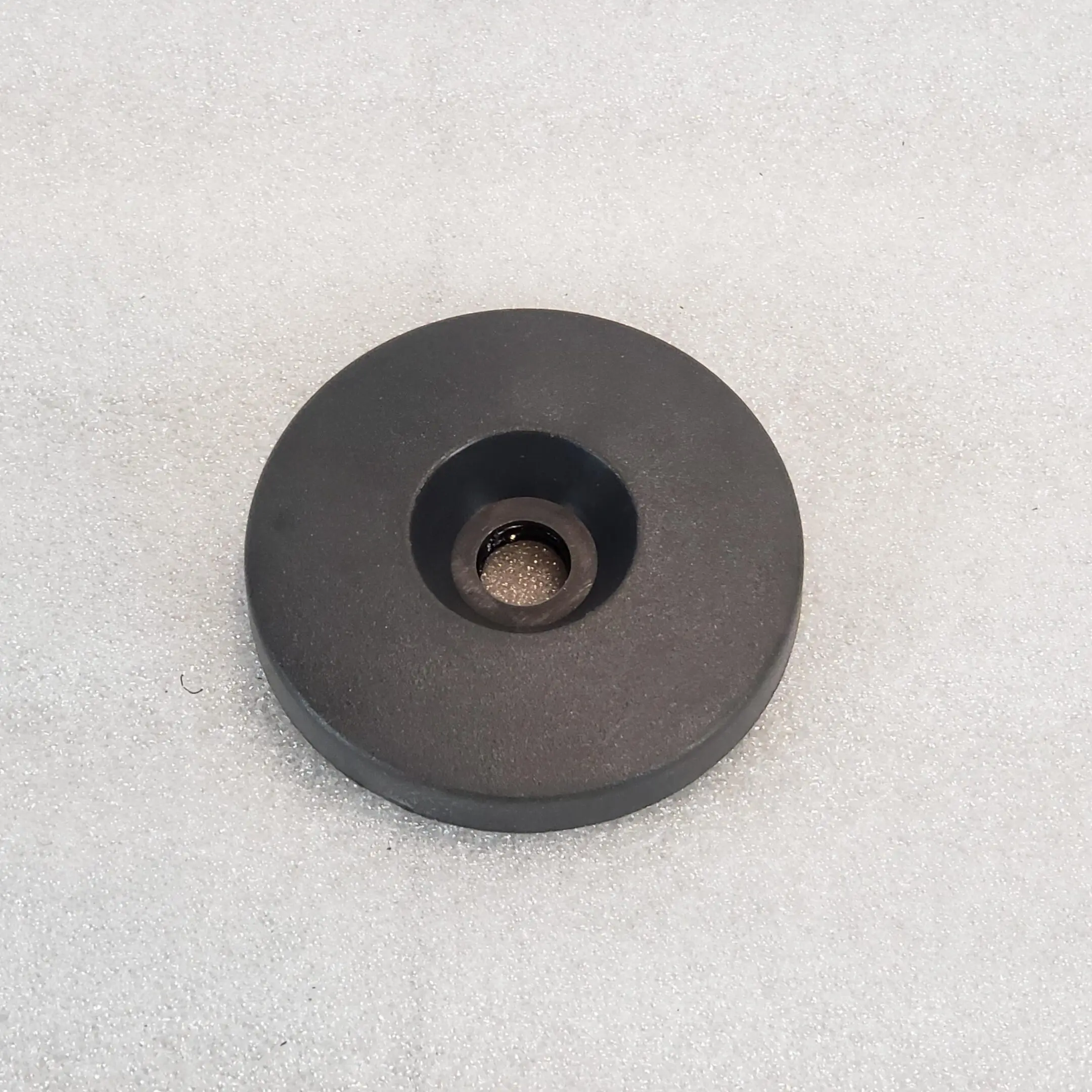 A black round object sitting on top of a white surface.