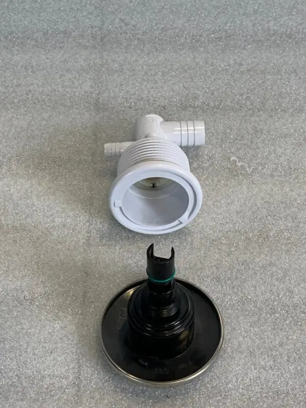 A white faucet and black knob on the floor.
