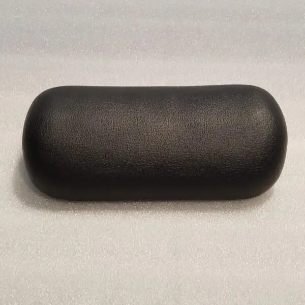 A black pillow sitting on top of a white table.