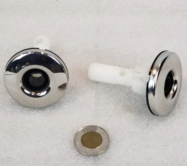 A pair of metal knobs with a small piece of plastic.