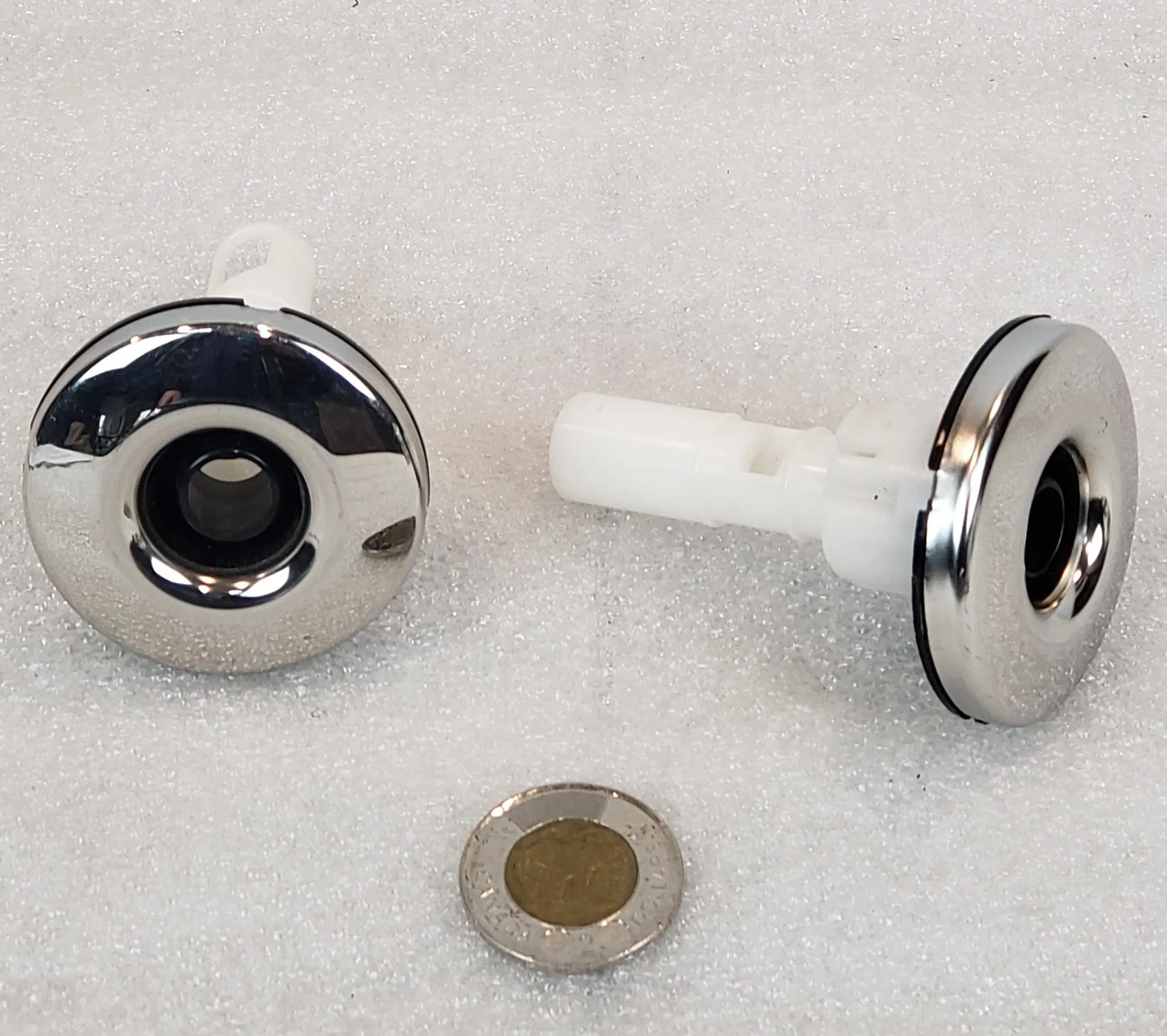 A pair of metal knobs with a small piece of plastic.