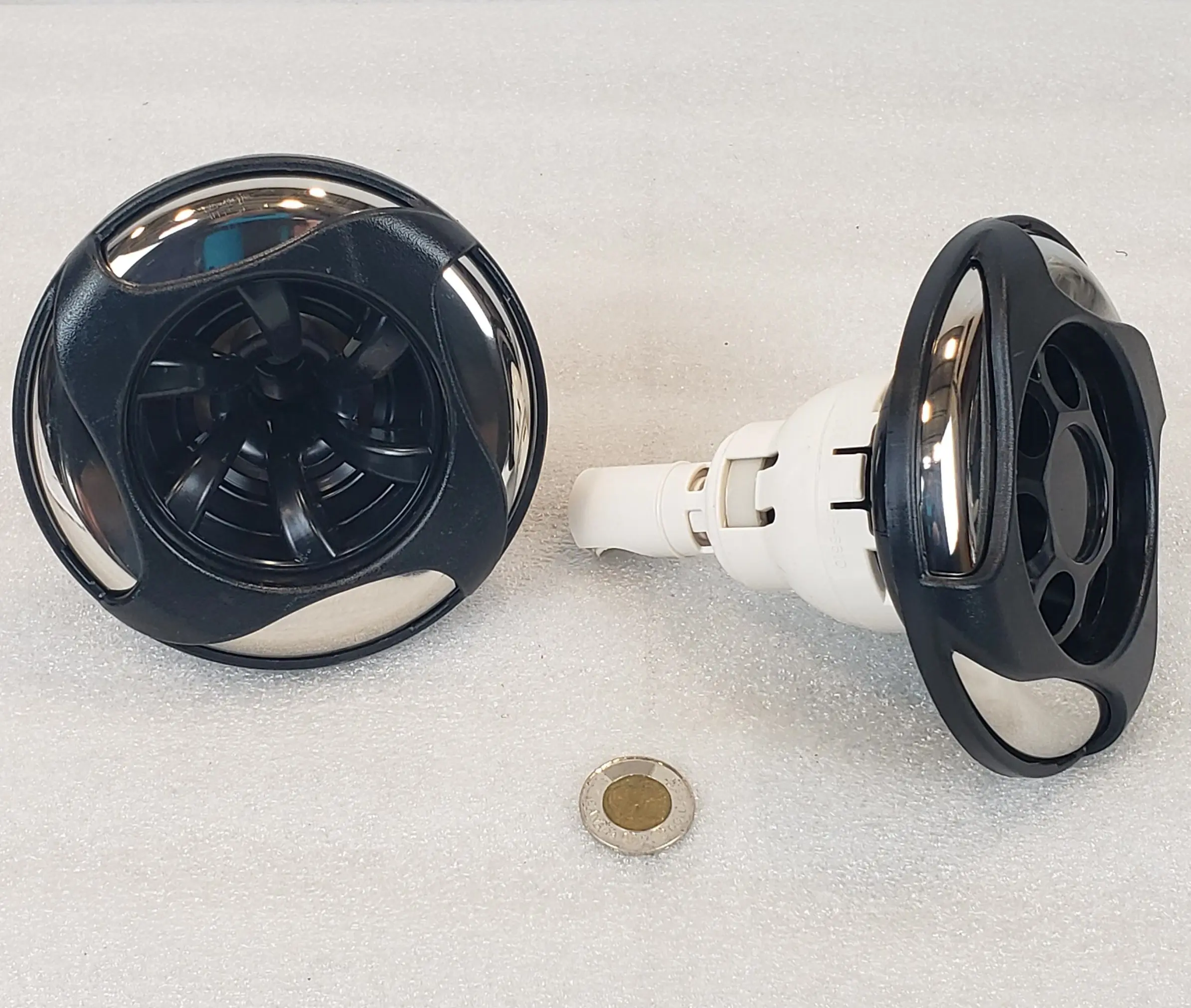 A pair of black and white knobs on the side of a sink.