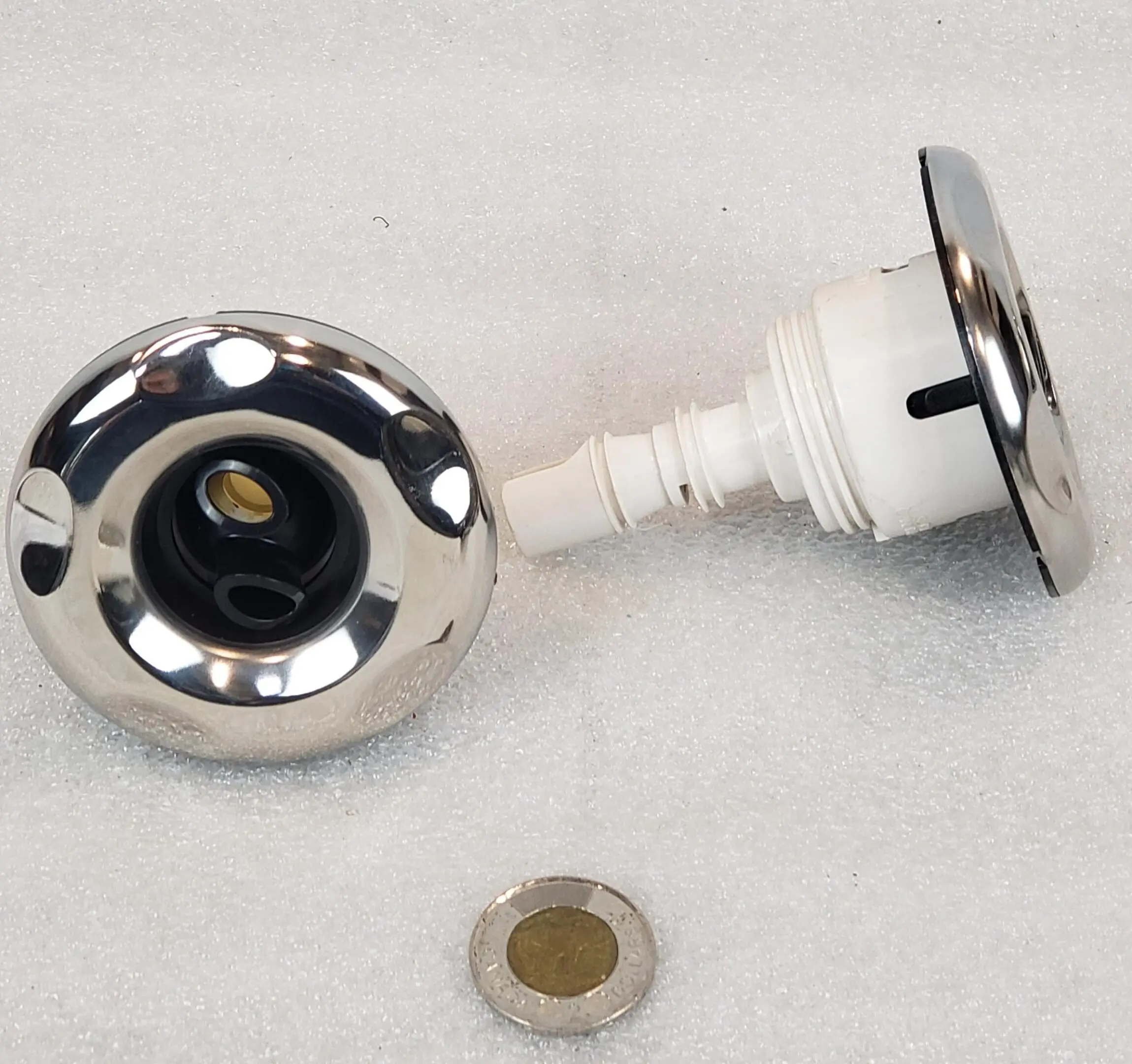 A chrome faucet with a white knob and a brown button.