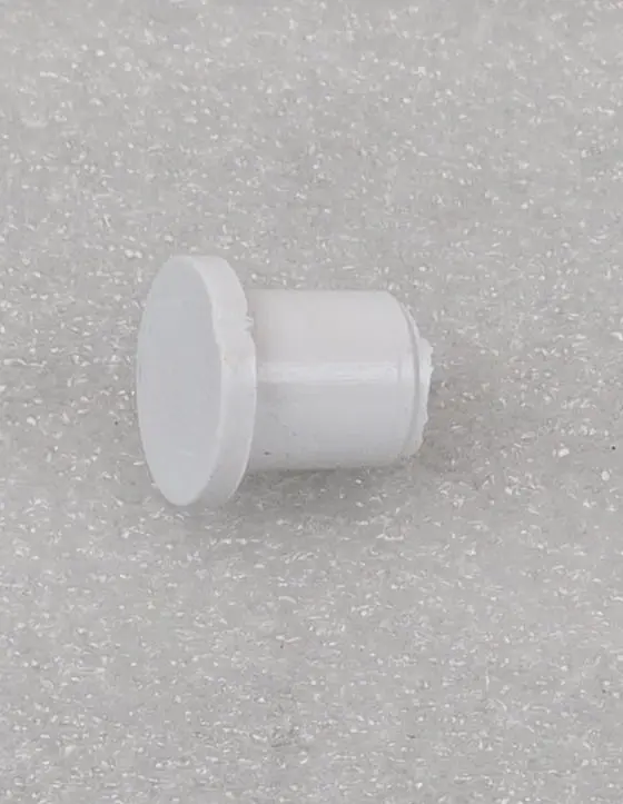 A white plastic button sitting on top of a floor.