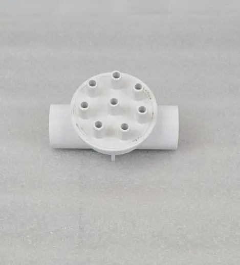 A white pipe with holes in it sitting on top of a floor.