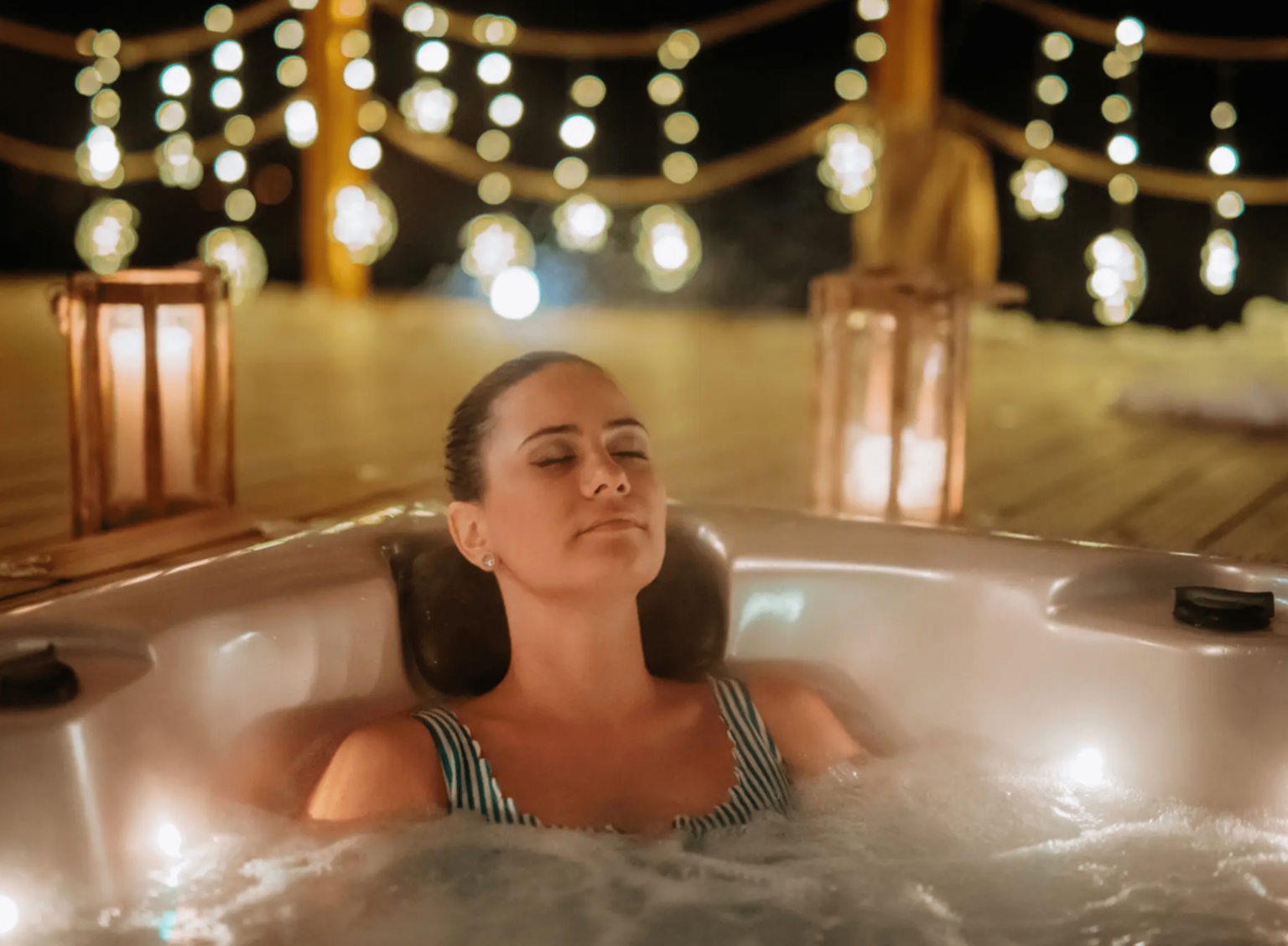 blob-11ec36e A woman sitting in a hot tub with lights around her.