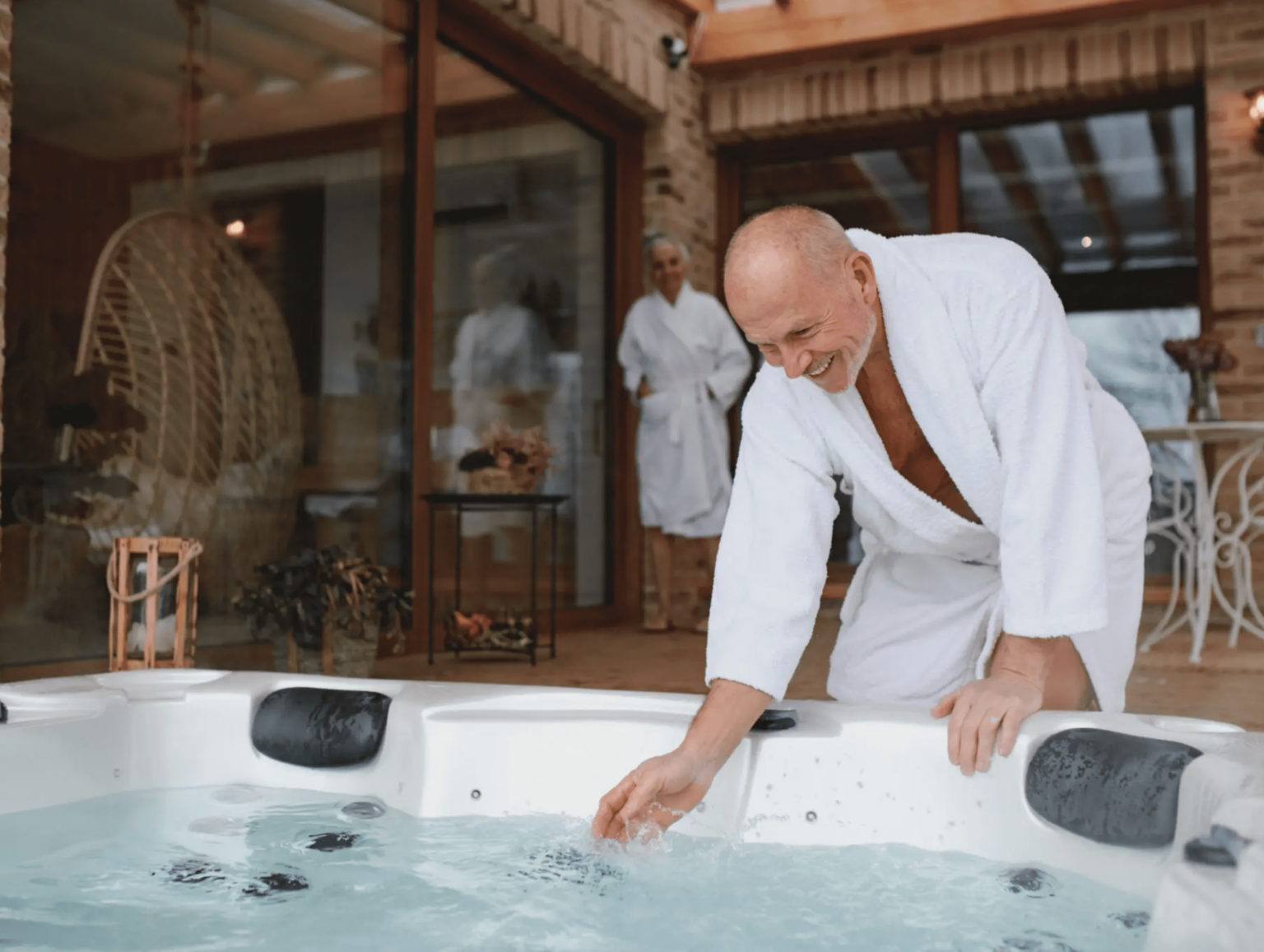 blob-529e551 A man in white robe touching the side of a hot tub.